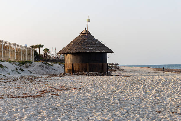 A small hut with a thatched roof stands on a pebble beach in Port El Kantaoui - Sousse - Tunisia - Africa