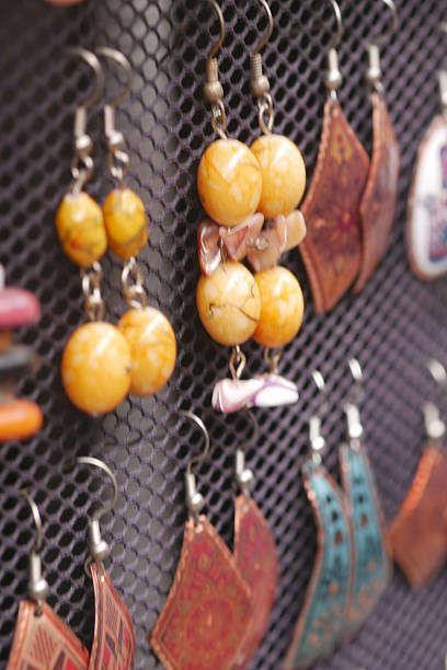 Vibrant yellow earrings hang on a mesh display at a market stall.