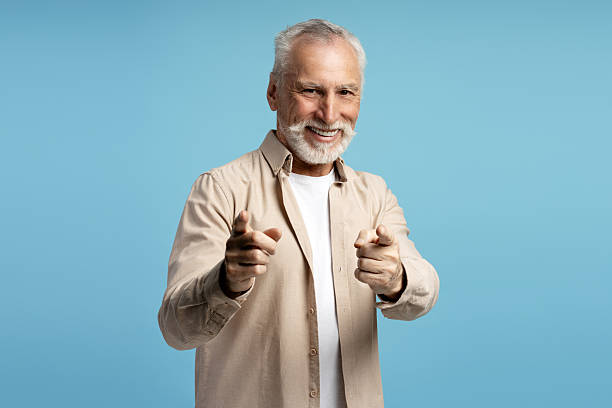 istock Smiling senior man pointing at you on blue background 2219673093