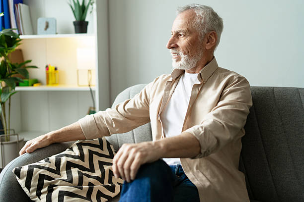 istock Smiling senior man relaxing on sofa at home, enjoying retirement looking away 2219673122