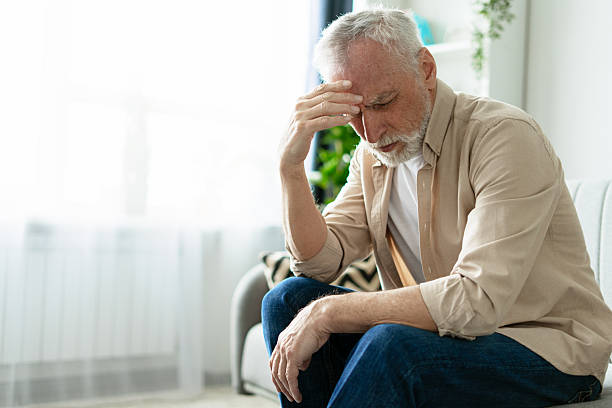 istock Senior man suffering from headache, touching forehead feeling pain at home 2219673136