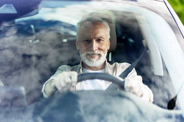 istock Senior man driving modern car and smiling looking at camera 2219673141