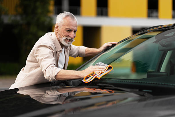 istock Smiling happy senior man cleaning car windshield with microfiber cloth 2219673181