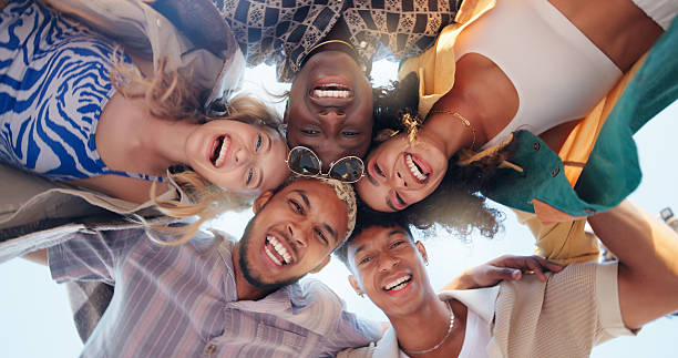 istock Happy people, friends and below with huddle for teamwork, community or support under blue sky background. Low angle, portrait or group with smile or hug in circle for solidarity, unity or trust 2219674101