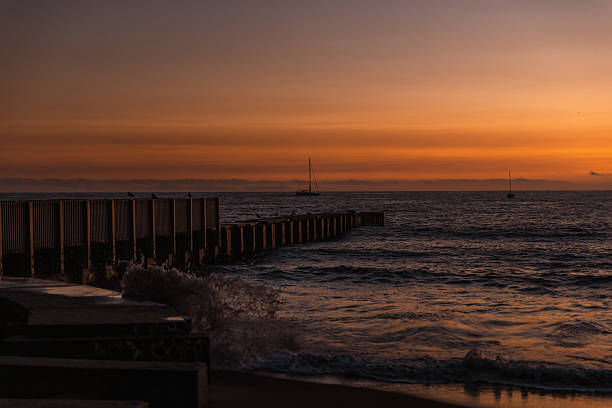 istock Sunset Over Ocean With Sand and Silhouetted Dock 2219674782