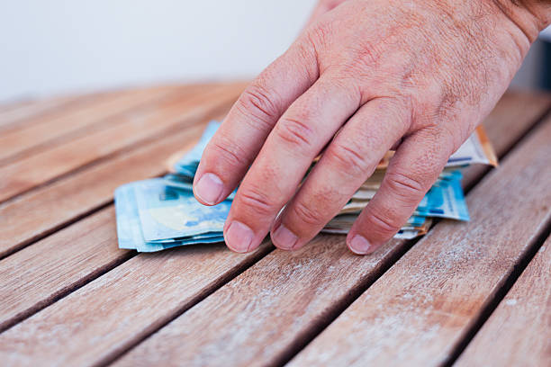 A man's hand is trying to take money, in a disguised way so that no one sees him as he does it with the utmost care. As if he were stealing