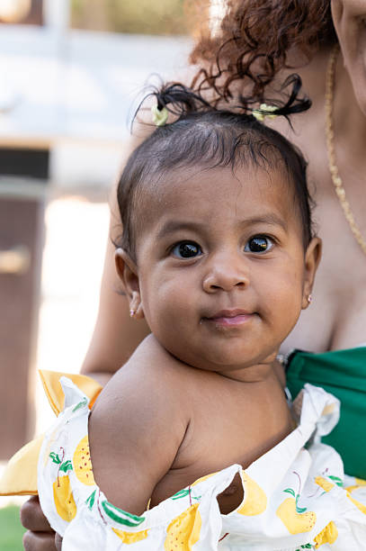 istock Adorable baby girl looking at camera while being held by mother 2219676973
