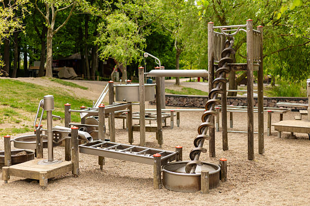 istock Children's playground showcases various metal play equipment designed for physical activity and exploration, set in a grassy area surrounded by trees during daylight 2219677249
