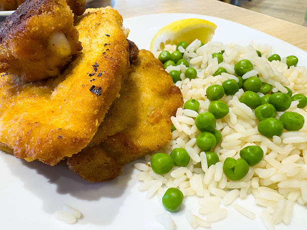istock Crispy breaded chicken with white rice and green peas on a plate 2219680538