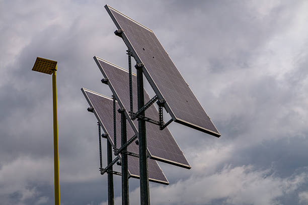 solar panels on a metal structure next to a yellow street lamp under a cloudy sky