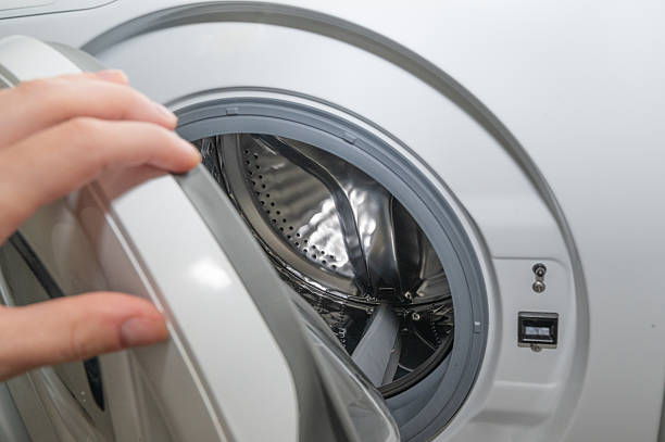 istock Hand opening washing machine door in modern laundry room 2219685504