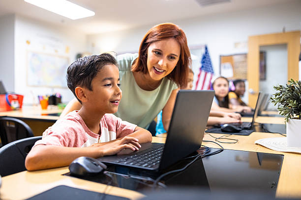 Elementary Students learning in the computer lab with their teacher stock photo