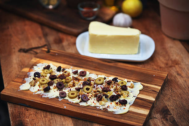 Hard yellow cheese, black and green olives, a sprig of dill on a wooden board. Flat Lay