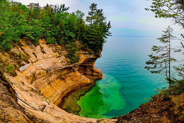 Blond woman walks alone along the shoreline covered in Rhyolite rocks at Iona Beach, also called Singing Beach for the tinkling sound heard when waves wash over the red rocks, Lake Superior, North Shore,  Two Harbors, Minnesota