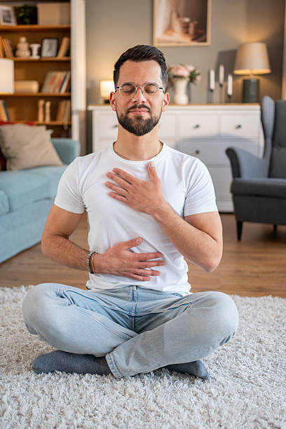 istock Young adult man practicing deep breathing exercise at home 2219695626