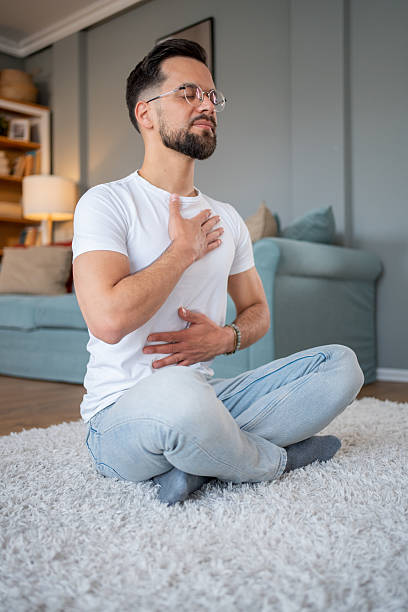 istock Young adult man practicing deep breathing exercise at home 2219695652