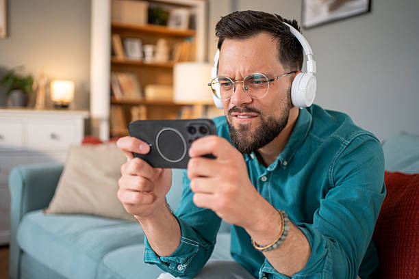 istock Focused man playing videogames on smartphone at home 2219696056