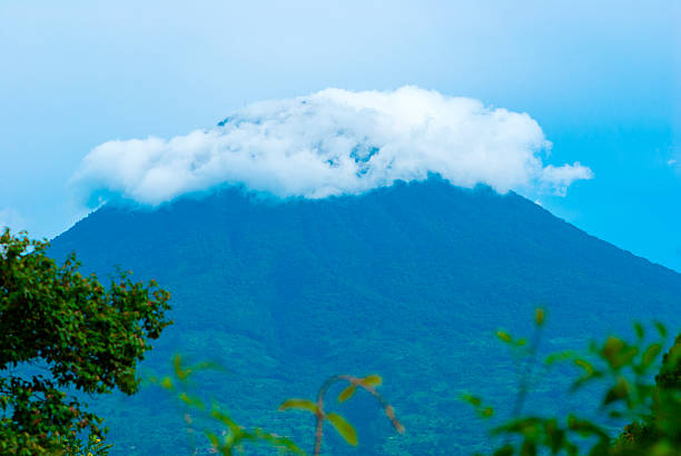 A majestic volcano in Guatemala rises through dense clouds and lush vegetation. A stunning view of Central America's tropical wilderness, rich biodiversity, and scenic mountain terrain.