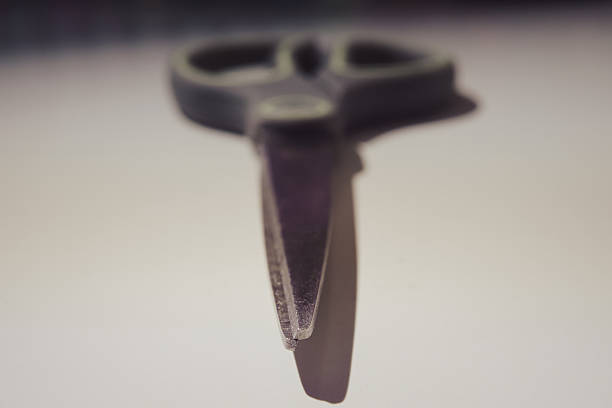 Scissor tip in focus, close up view, blurred background.