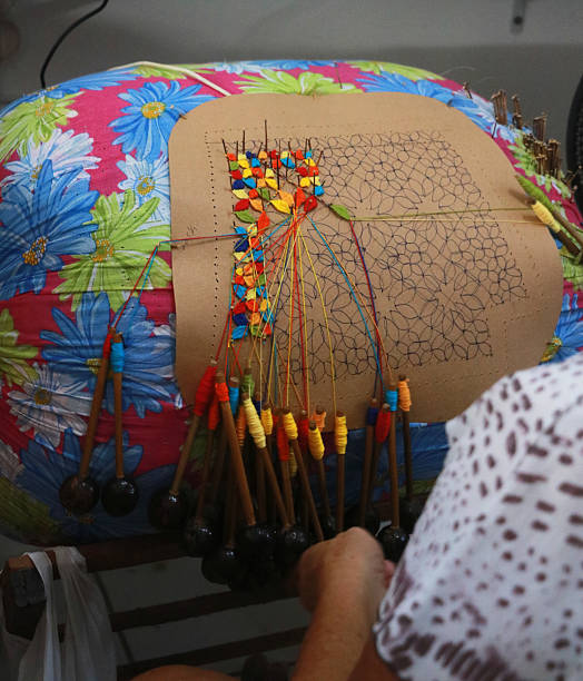 Bobbin (Bilro) lace production. Elderly woman's hands weaving exquisite lace. Traditional craftsmanship from Ceará. Bobbin lace in progress, an amazing textile art. Aquiraz, Ceará