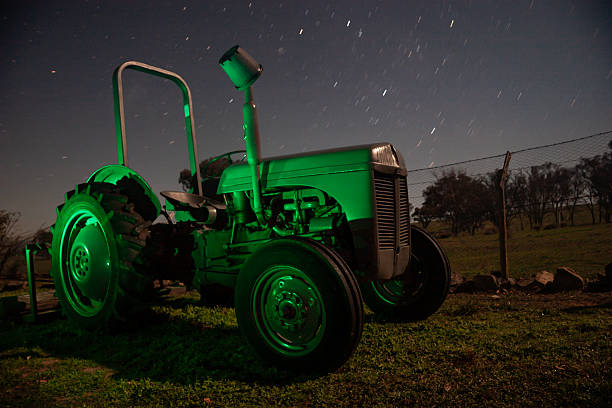 A classic grey Ferguson tractor positioned in a rural paddock beneath a canopy of stars.