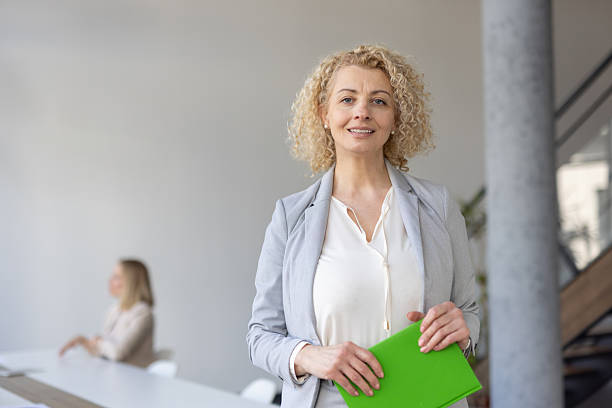 istock Professional woman in a soft gray suit holding a folder. 2219706235