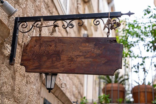 istock Rustic blank wooden sign on iron bracket in vintage street setting 2219706396