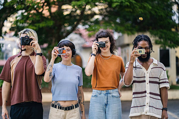 Group of young friends interacting with old analog cameras