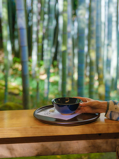 Clay teapot and teacups with drops of tea on bamboo tray during ritual tea serving.