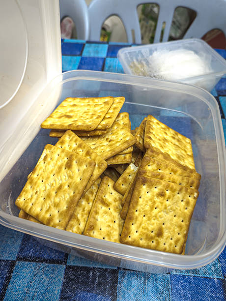 Cream crackers are stacked in a clear plastic container.