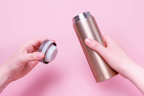 istock Female hand holding thermo mug on pink background close-up. 2219721019