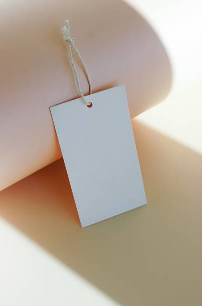 istock Cardboard tag, blank tag tied with string, space for text on abstract shadow beige background 2219728031
