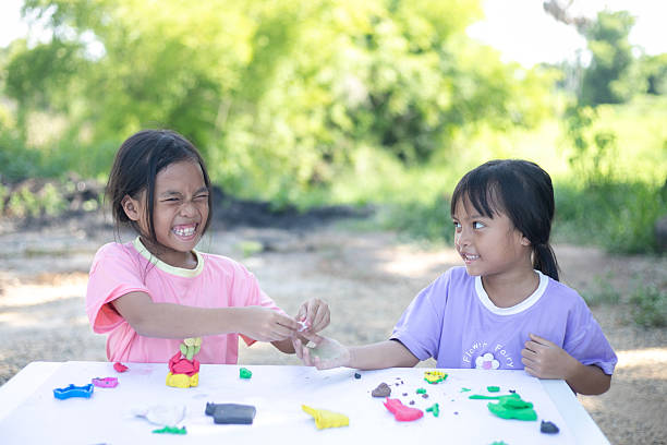 istock Two young girls are playing with clay on a table 2219733491