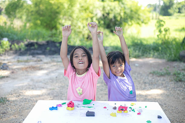 istock Two young girls are sitting at a table playing with clay 2219733532