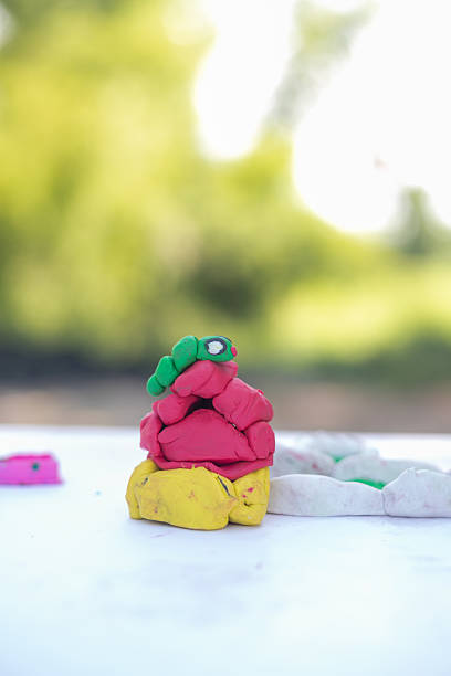 Smiling latin preschool kid boy having fun with dough, colorful modeling compound clay animals as a turtle, tiger and more in his bedroom studio.