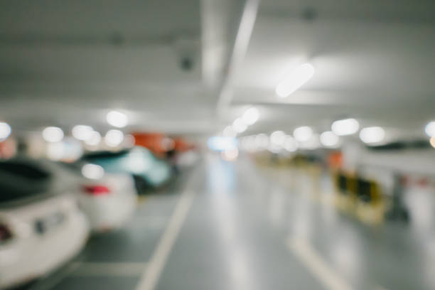 istock Bokeh for background. Blurred Interior of a Modern Parking Garage with Illuminated Spaces and Vehicles in Entangled Perspective 2219735932