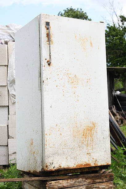 istock Old rusted refrigerator standing on a wooden pallet in a rural setting 2219737804