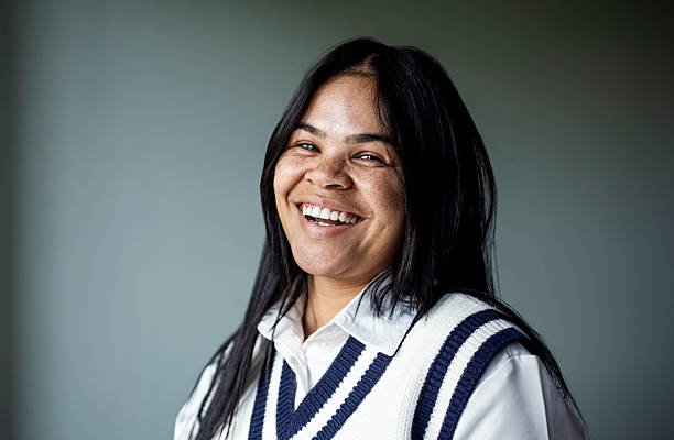 Studio portrait of a cheerful young woman smiling at camera against gray backdrop