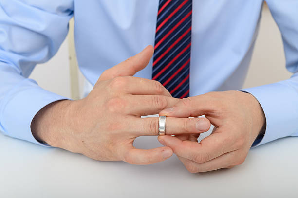 istock Man takes off his wedding ring, divorce separation concept 2219743924