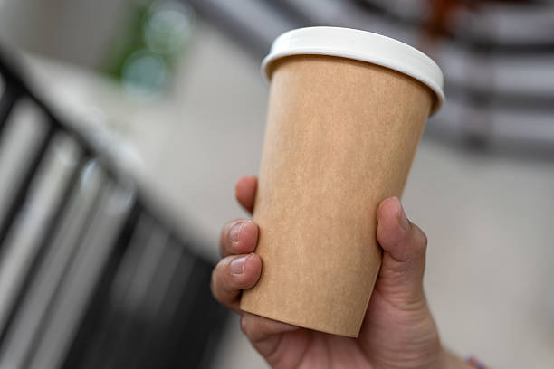 istock A hand firmly holds a brown paper cup with a white lid. 2219745778