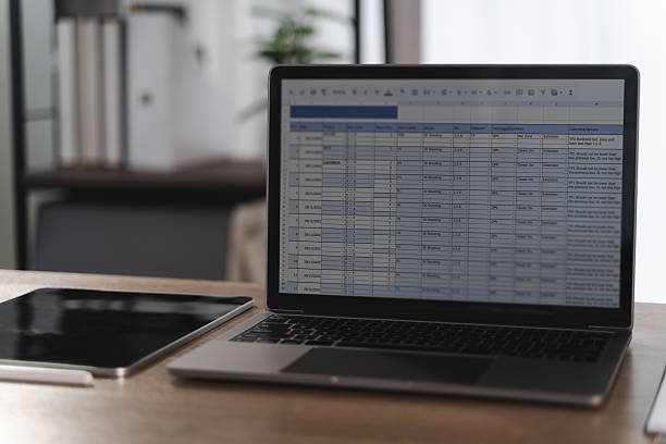 istock Report file laptop displaying spreadsheet with data and charts wooden desk modern office environment, with tablet and pen nearby, creating 2219751625