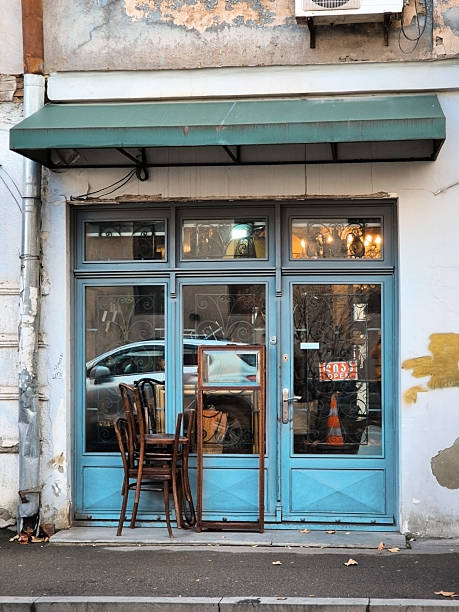 Vintage furniture store in Tbilisi with stacked chairs and an old frame outside, charming blue door and weathered facade. stock photo