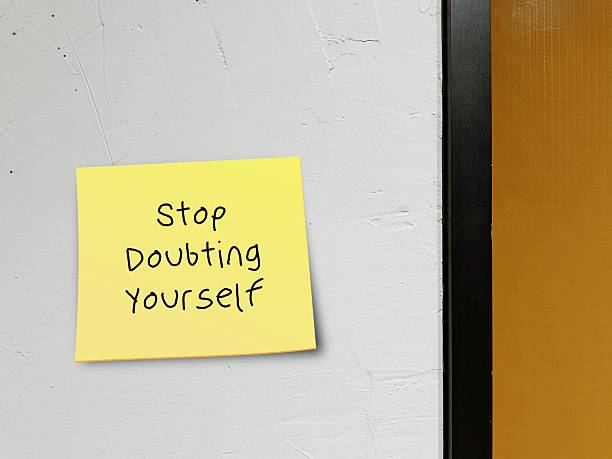 istock Stick note on wall background with handwritten STOP DOUBTING YOURSELF, concept of self-doubt - lack of confidence  mindset that holds you back from succeeding leads to imposter syndrome or self-sabotage 2219754005