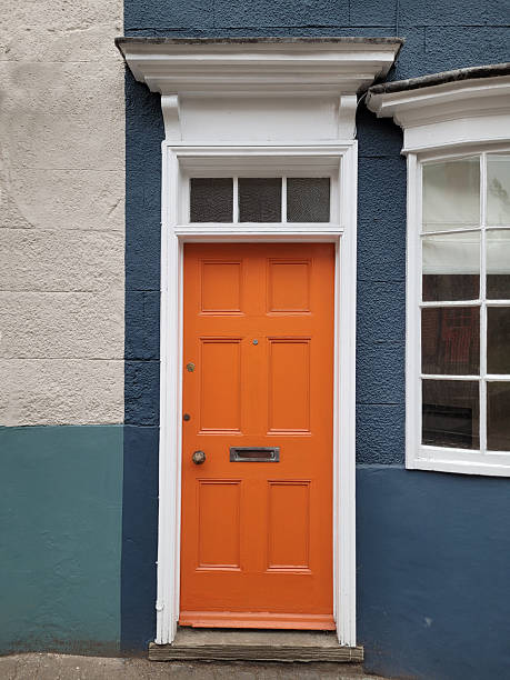 istock Modern, bright orange front door against a white and blue stone wall 2219754590