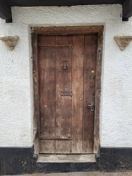 istock Old wooden front door against a white, stone wall 2219754625