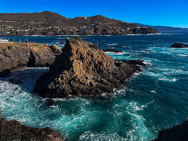 Rocky Coastline with Crashing Waves and Distant Hills