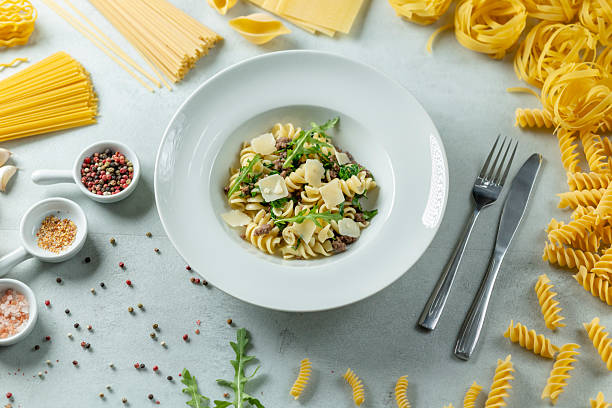 istock Fusilli pasta dish with parmesan, arugula and minced meat surrounded by various types of pasta and spices 2219757644