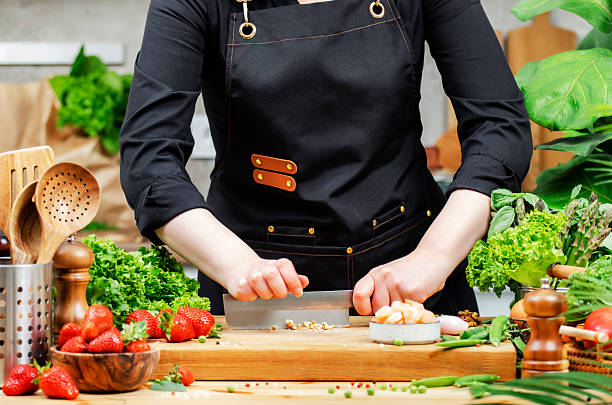 istock skilled chef in stylish black apron chops walnuts and fresh vegetables and fruits, creating a healthy vegan meal. The vibrant kitchen with organic produce, showcasing food blogging culinary creativity. 2219758587