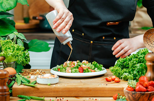 istock Chef skillfully prepares healthy salad, drops sauce on full plate, using fresh vegetables and vibrant ingredients 2219758632