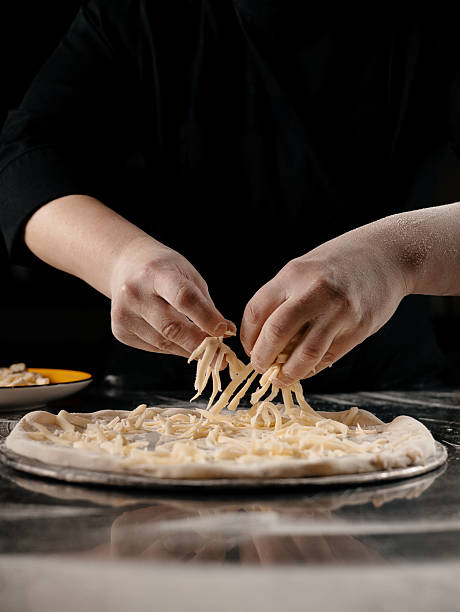 Chef Sprinkling Cheese on Pizza Dough